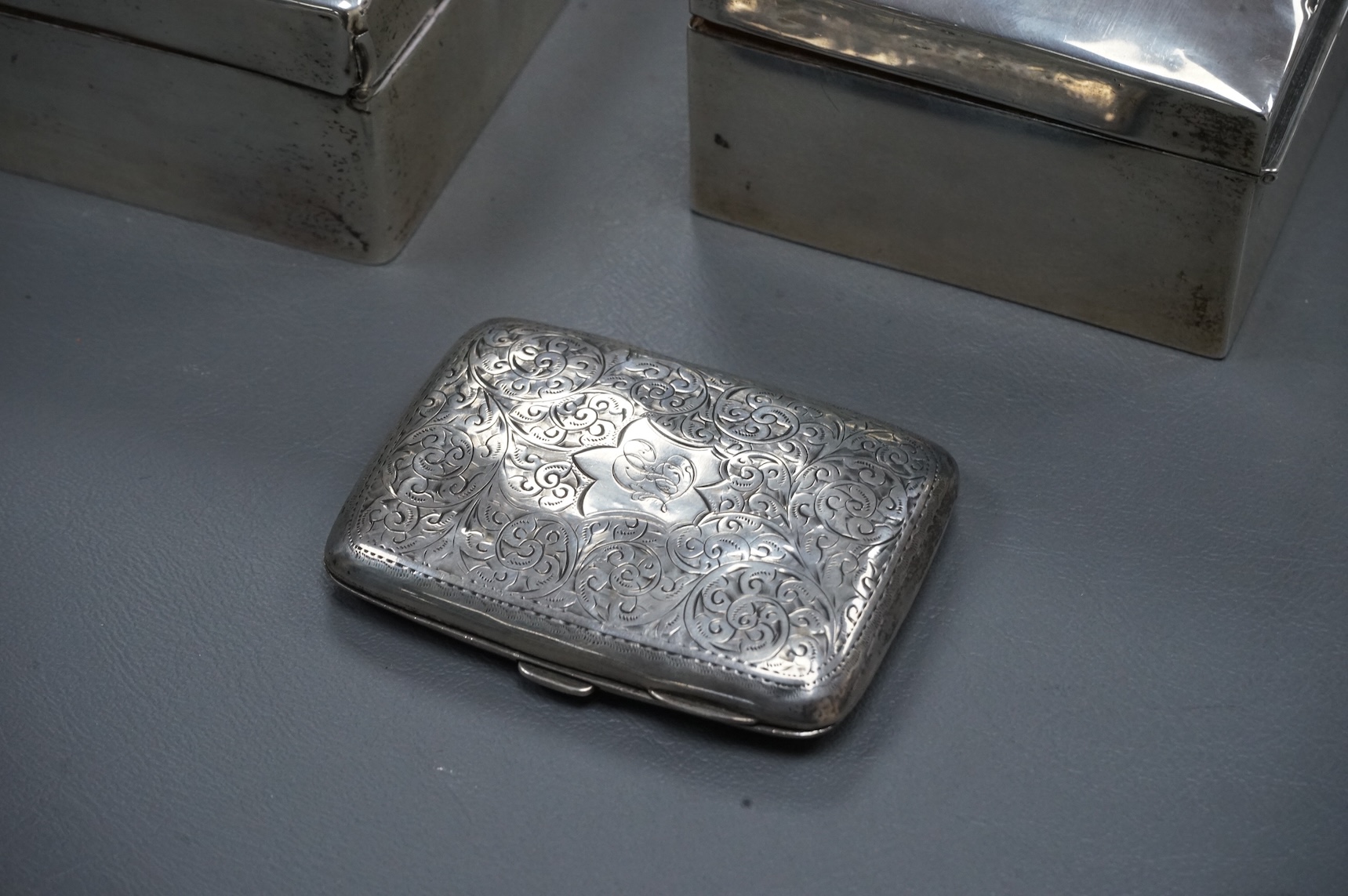 A George V silver mounted rectangular cigarette box, London, 1924, width 16cm, together with a smaller silver mounted cigarette box and a silver cigarette case.